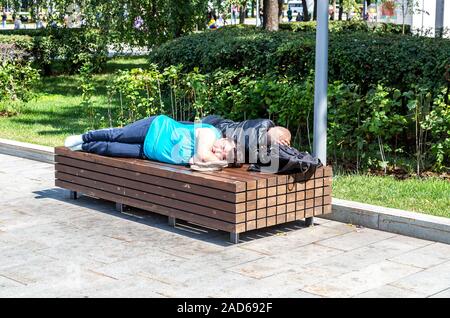 Moskau, Russland - Juli 8, 2019: Obdachlose schlafen auf der Holzbank im City Park Stockfoto