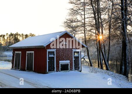 Sonnenuntergang am Perniönjoki Fluss an einem kalten Dezember Nachmittag mit einem kleinen rustikalen Lagergebäude. Ristinkulma, Salo, Finnland. Stockfoto