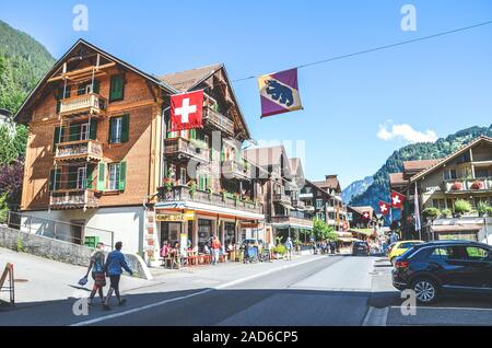 Lauterbrunnen, Schweiz - 16. Juli 2019: Hauptstraße im malerischen Bergdorf Lauterbrunnen im Sommer fotografiert. Traditionelle Holzchalets, Geschäften, Restaurants, Leute. Stockfoto