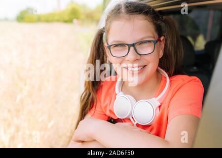 Süß lächelnde Mädchen mit Kopfhörern im Freien Stockfoto