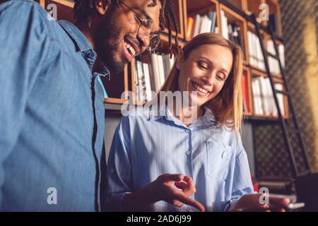 Junge lächelnde business Mann und Frau zusammen, die im Büro der Analyse der positiven Ergebnisse Stockfoto