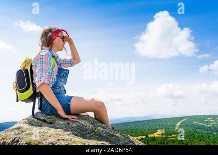 Young Travel Mädchen sitzen auf dem Rock Mountain mit Rucksack, entspannend - jugendlich Wanderer Mädchen entspannen und genießen Blick auf das Tal Stockfoto