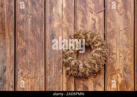 Stroh Kranz auf hölzernen Tür Stockfoto