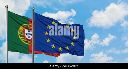 Portugal und die Fahne der Europäischen Union winken im Wind gegen Weiße bewölkt blauer Himmel zusammen. Diplomatie Konzept, internationale Beziehungen. Stockfoto