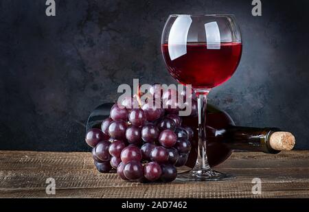 Glas Wein mit Trauben und Flasche Stockfoto