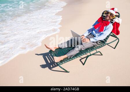 Entspannt Büroangestellter arbeiten auf seinem Laptop an einem tropischen Strand Urlaub Stockfoto