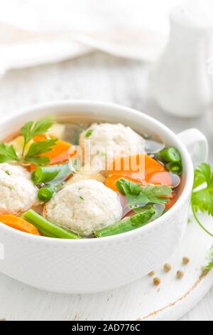 Frische Hühnersuppe mit Gemüse und Fleischbällchen in einer Schüssel auf weißem Hintergrund. Ansicht von oben Stockfoto