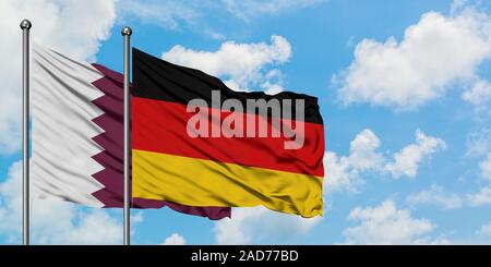 Katar und Deutschland Fahne im Wind gegen Weiße bewölkt blauer Himmel zusammen. Diplomatie Konzept, internationale Beziehungen. Stockfoto