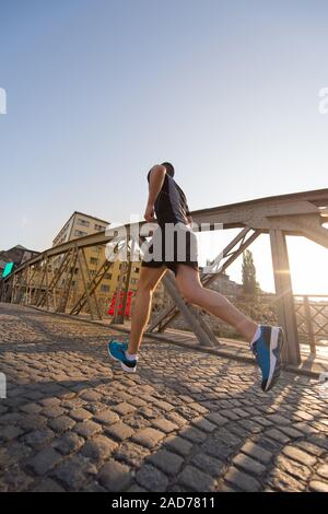 Man joggen auf der anderen Seite der Brücke am sonnigen Morgen Stockfoto
