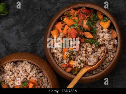 Vegan Buchweizengrütze gekocht mit Karotte und gerösteten Bellpepper in hölzernen Schüsseln serviert. Stockfoto