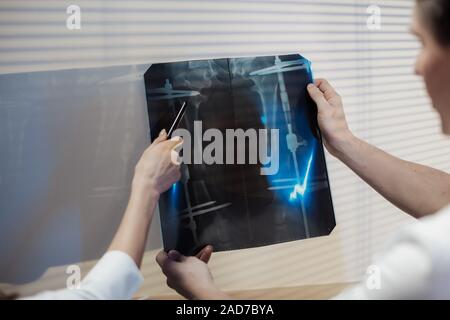 Zwei Ärzte untersuchen die x-ray Bild. Arzt das Mädchen und der Mann die Diagnose zu besprechen. Stockfoto