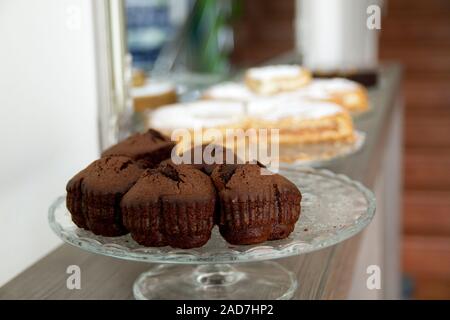 Schokolade in Herzform Muffins auf einem Glas Kuchen stehen mit unscharfen Apple Pies in den Hintergrund. Stockfoto