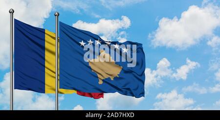 Rumänien und dem Kosovo Flagge im Wind gegen Weiße bewölkt blauer Himmel zusammen. Diplomatie Konzept, internationale Beziehungen. Stockfoto