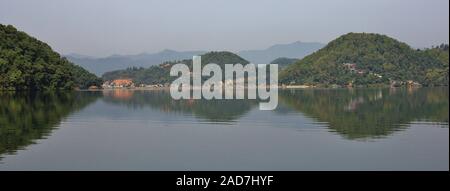 Morgen Szene an begnas See, Nepal. Hügel von Wald Spiegelung im Wasser, bedeckt von Majhj Stockfoto