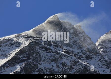 Schnee durch starke Winde über einen hohen Berg gesprengt. Stockfoto