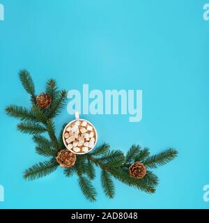 Trendy Weihnachten Hintergrund von heißer Schokolade mit Eibisch, Weihnachtsbaum, Zweige mit goldenen Kegel auf cyan blau Hintergrund. Ferienzeit Konzept Stockfoto