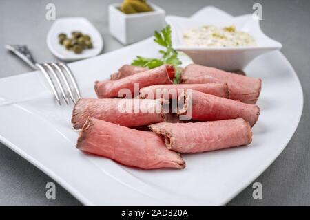 Traditionelles Mittagessen Fleisch mit in Scheiben geschnittenen Wurst Roastbeef und Remoulade als Closeup auf eine weisse Platte Stockfoto