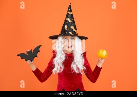 Freakishly wicked Halloween. Wenig böse Hexe Kind bat und Kürbis. Glückliches Mädchen tragen böse Hexe Kostüm. Kleine böse Zauberin mit modischen und schrecklich aussehen. Stockfoto