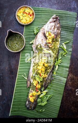 Grill Weißen Zackenbarsch mit chimichurri Sauce aji Criollo und Mango Chutney, Ansicht von oben in einem grünen Banana leaf Stockfoto