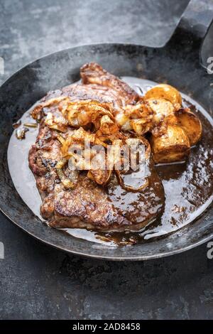 Traditionelle trockenen Jahren in Scheiben Roastbeef mit gebratenen Zwiebeln und Kartoffel Chips, Nahaufnahme in einem wrough - eiserne Pfanne mit Brauner Soße Stockfoto