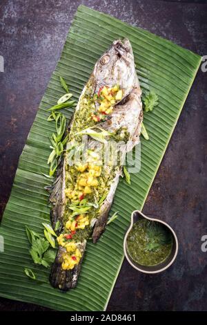 Grill Weißen Zackenbarsch mit chimichurri Sauce aji Criollo und Mango Chutney, Ansicht von oben in einem grünen Banana leaf Stockfoto