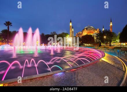 Schöne Hagia Sophia und Hamam in Istanbuls Altstadt timelapse mit blau beleuchteten Brunnen, Sultanahmet, Türkei. Reflexion auf dem Wasser Stockfoto