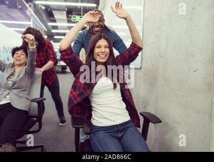 Multiethnics Business Team Racing auf Bürostühle Stockfoto