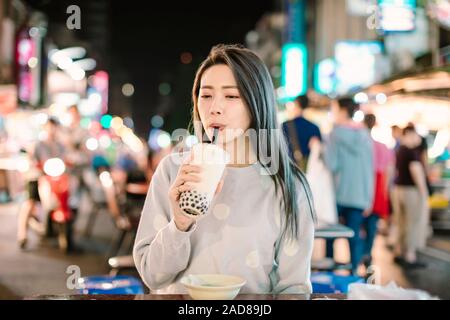 Asiatische Frau genießen bubble Milch Tee mit Street Food in der Nacht Markt Stockfoto