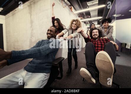 Multiethnics Business Team Racing auf Bürostühle Stockfoto