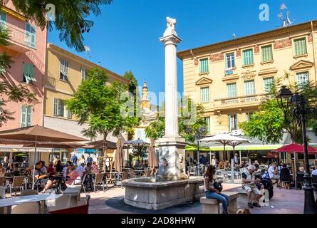 Einheimische, Touristen und einem sonnigen Nachmittag an einem kleinen Platz im Zentrum der Altstadt von Menton, Frankreich, an der Französischen Riviera. Stockfoto