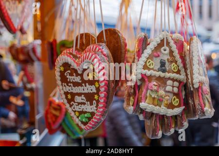 Nahaufnahme der Lebkuchen mit "Frohe Weihnachten" bedeutet, dass fröhliche Weihnachten vor dem Festladen am Weihnachtsmarkt in Weihnactsmarkt hängen. Stockfoto