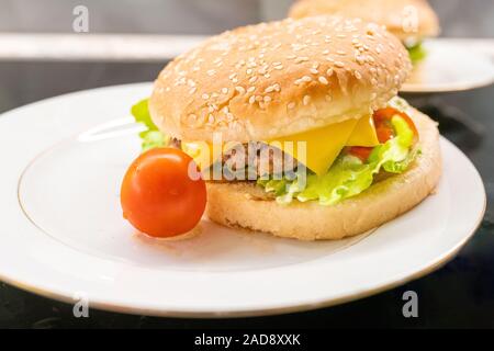 Hausgemachte Hamburger mit Cherry Tomaten auf der Platte Nahaufnahme. Selektiver Fokus Stockfoto