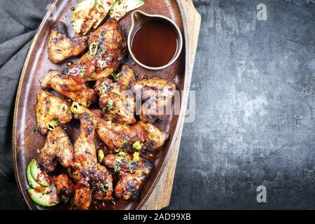 Traditionelle Grill Chicken Wings und Keulen mit Hot Chili Sauce als Draufsicht auf einem Teller mit Kopieren nach rechts Stockfoto