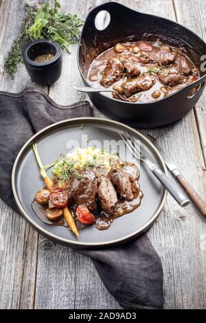 Traditionelle deutsche Geschmorte Schweinebäckchen in Braune Sauce mit Pilzen und Kartoffelpüree als Closeup auf ein modernes Design Platte Stockfoto