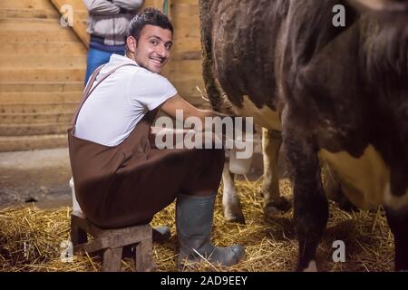 Landwirt Milchkuh Melken von Hand Stockfoto