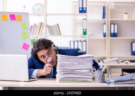 Junge männliche Mitarbeiter mit übermäßiger Arbeit unzufrieden Stockfoto