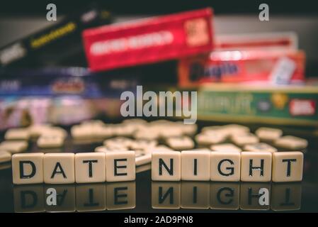 Datum Nacht in Brief Fliesen auf schwarzem Hintergrund geschrieben mit Brettspiele im Hintergrund Stockfoto