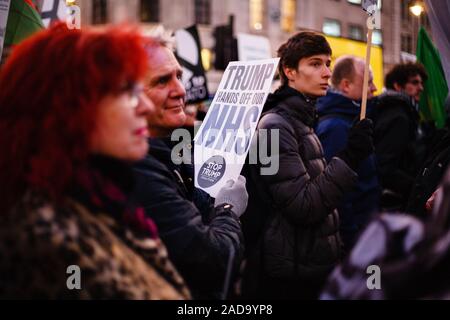 London, Großbritannien. 03 Dez, 2019. Ein Aktivist hält ein Plakat gegen jede Post-Brexit uns den Zugang zum Markt der britische National Health Service (NHS) während der Demonstration. Präsident Trump kam in Großbritannien auf einem dreitägigen Besuch in der vergangenen Nacht, vor allem der NATO-Gipfel in Watford zu besuchen. Aktivisten protestieren gegen die Trumpf Besuch auf dem Trafalgar Square. Credit: SOPA Images Limited/Alamy leben Nachrichten Stockfoto