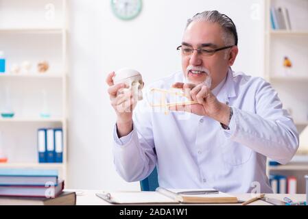 Alter männlicher Arzt mit Skelett Stockfoto