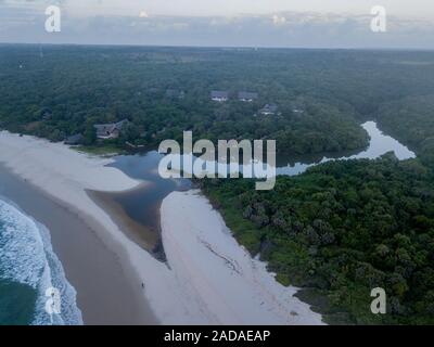 Drone Bild von Gebäuden im Wald durch den Ozean. Stockfoto