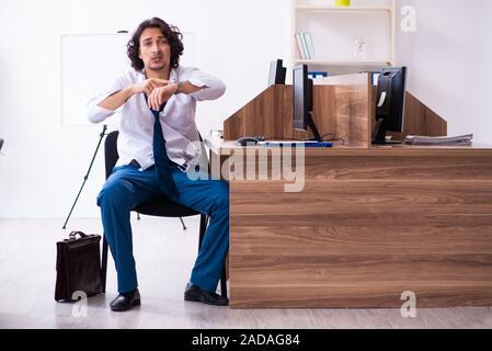 Junge männliche Mitarbeiter mit übermäßiger Arbeit unzufrieden Stockfoto