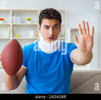 Mann mit Nackenschmerzen beobachten, American Football zu Hause Stockfoto