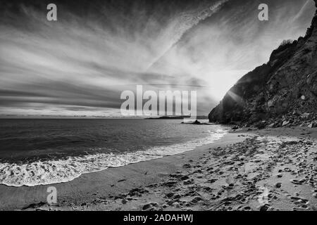 Die Sonne schön hinter den Klippen von St. Austell, Cornwall, England. Die Leute haben bereits den Strand verlassen. Stockfoto