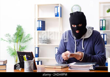 Männliche Dieb in Balaclava im Büro Stockfoto