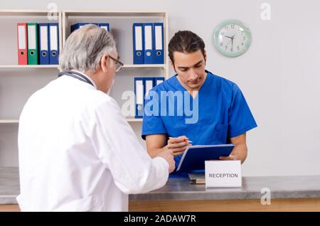 Zwei Ärzte im Gespräch an der Rezeption im Krankenhaus Stockfoto