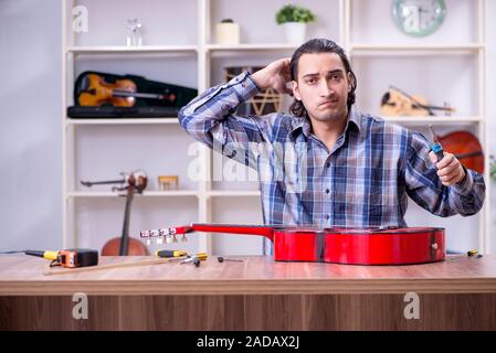 Junge schöne Handwerker Reparatur Gitarre Stockfoto