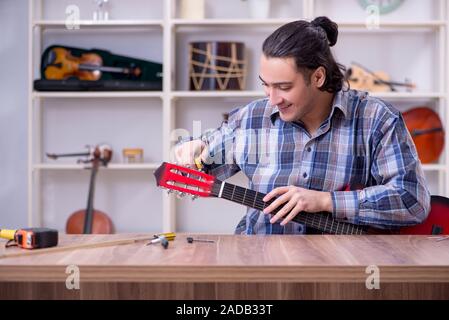 Junge schöne Handwerker Reparatur Gitarre Stockfoto
