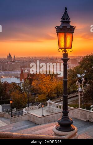 Budapest, Ungarn - Farbenfroher Herbstmorgen in Budapest. Straßenlaterne an der Fischerbastion, der Stephansbasilika und der wundervolle goldene Sonnenaufgang Stockfoto