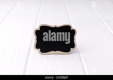 Leeren schwarzen Hinweis Schild auf weißem Holz- Hintergrund. Mock up Vorlage mit Kopie Raum Stockfoto
