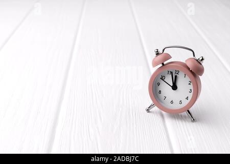 Retro Style pink Wecker auf weißem Holz- Hintergrund zeigt zwei Minuten vor zwölf Uhr. Zeit aufzuwachen Vorlage mit Kopie Raum Stockfoto